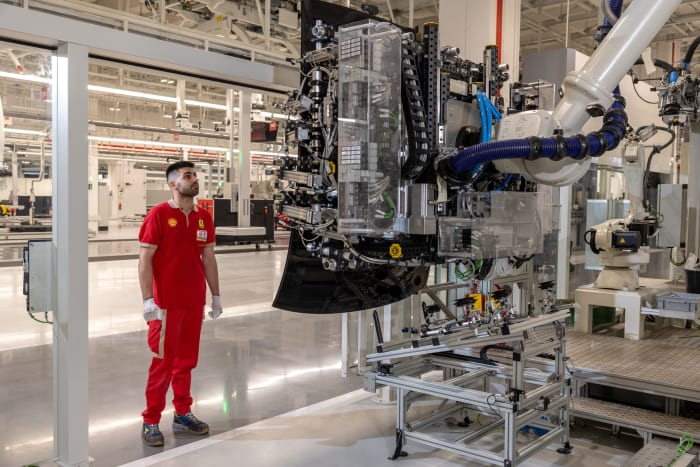 A Ferrari factory worker surveys the job being done by one of countless high-tech robots used for jobs that help humans keep the line humming efficiently