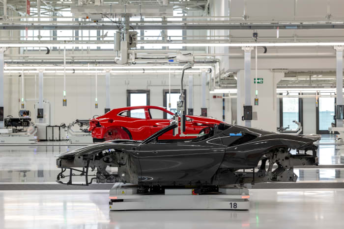 Freshly painted Ferrari car bodies pass each other on movable platforms inside the Ferrari factory