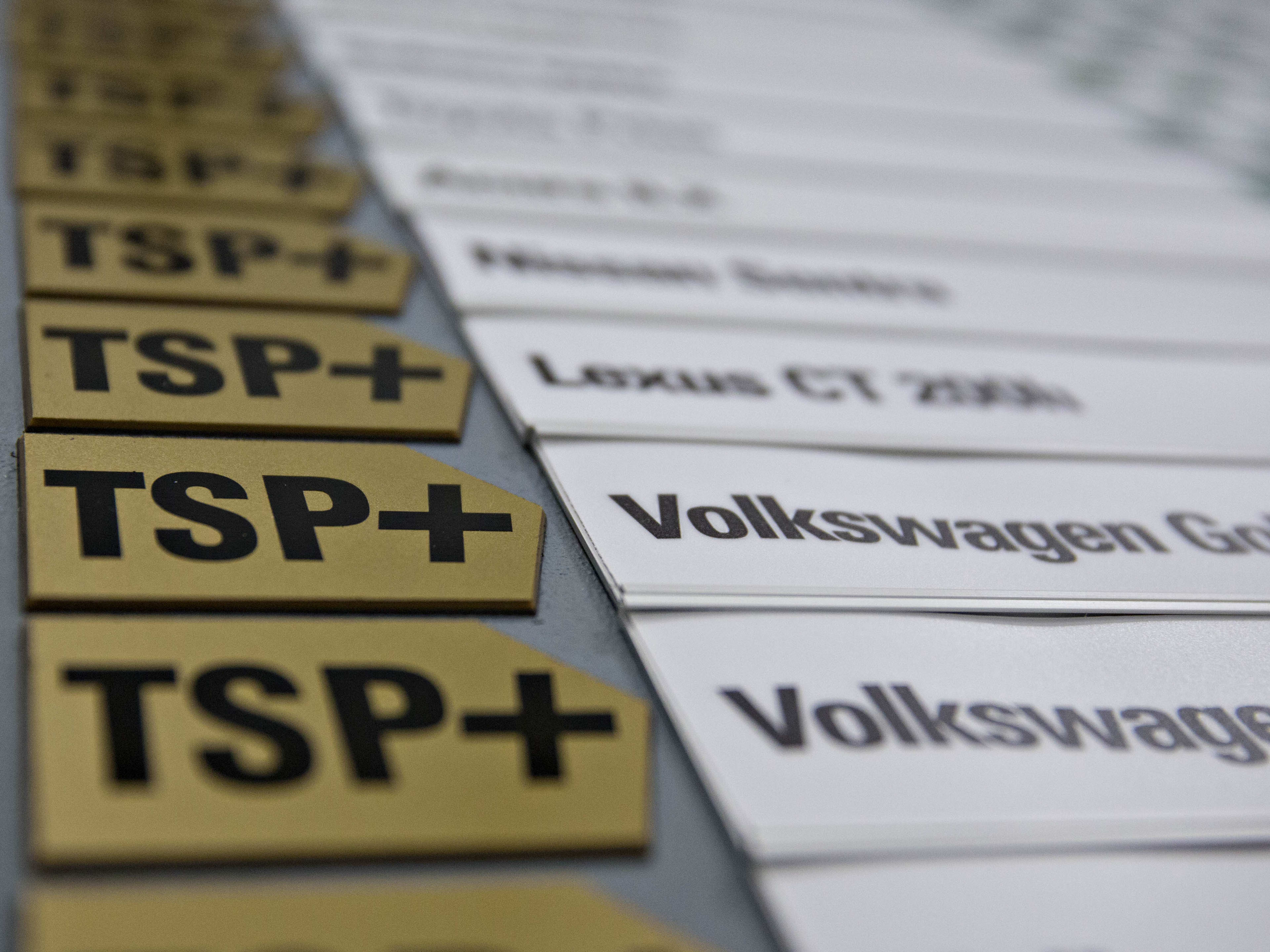 Insurance Institute for Highway Safety (IIHS) Top Safety Pick (TSP) badges are displayed next to vehicles on a wall at IIHS headquarters.