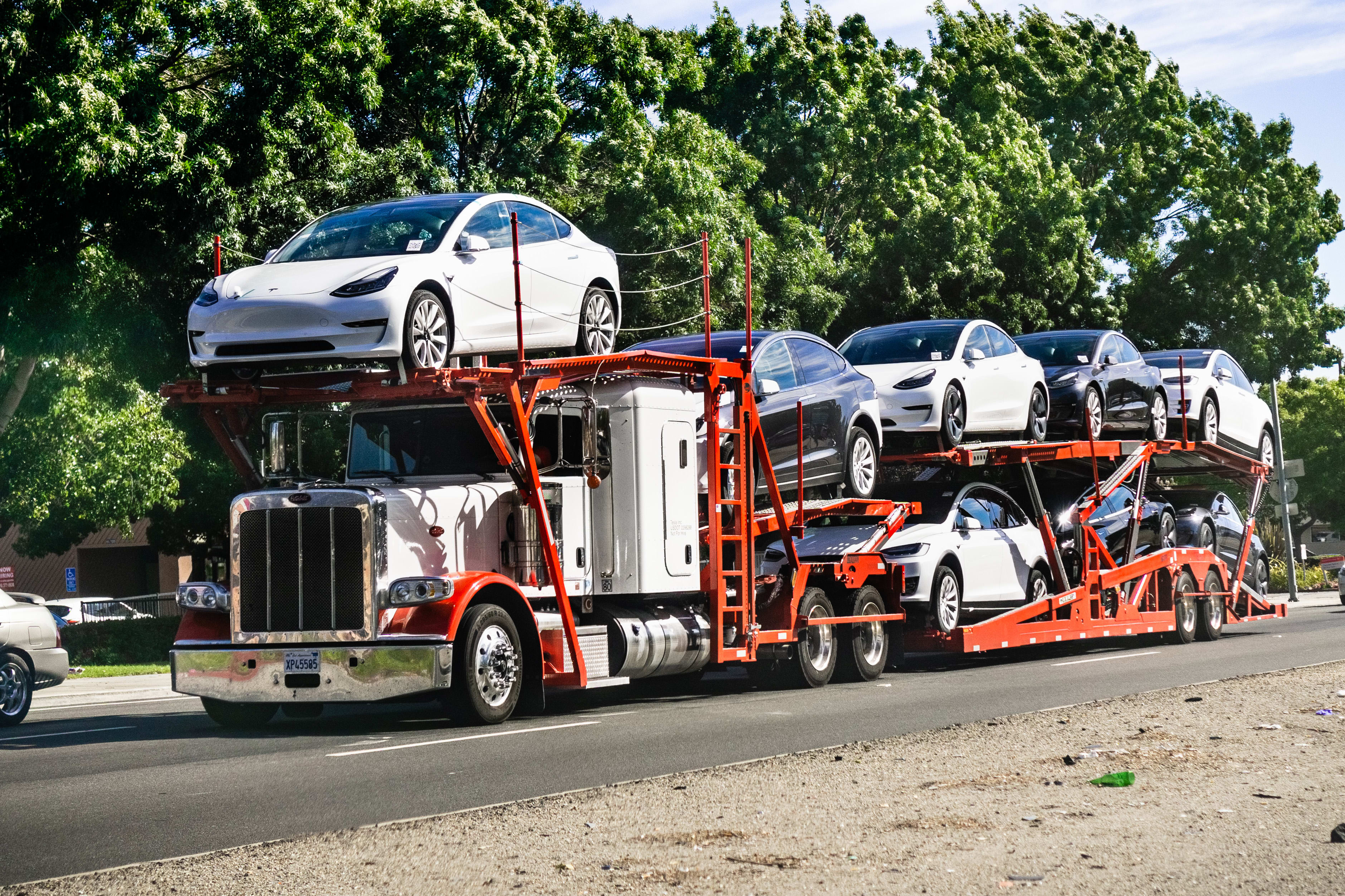 June 28, 2019 Fremont / CA / USA - Car transporter carries Tesla Model 3 new vehicles from the nearby company factory, East San Francisco bay area, front view of the trailer;