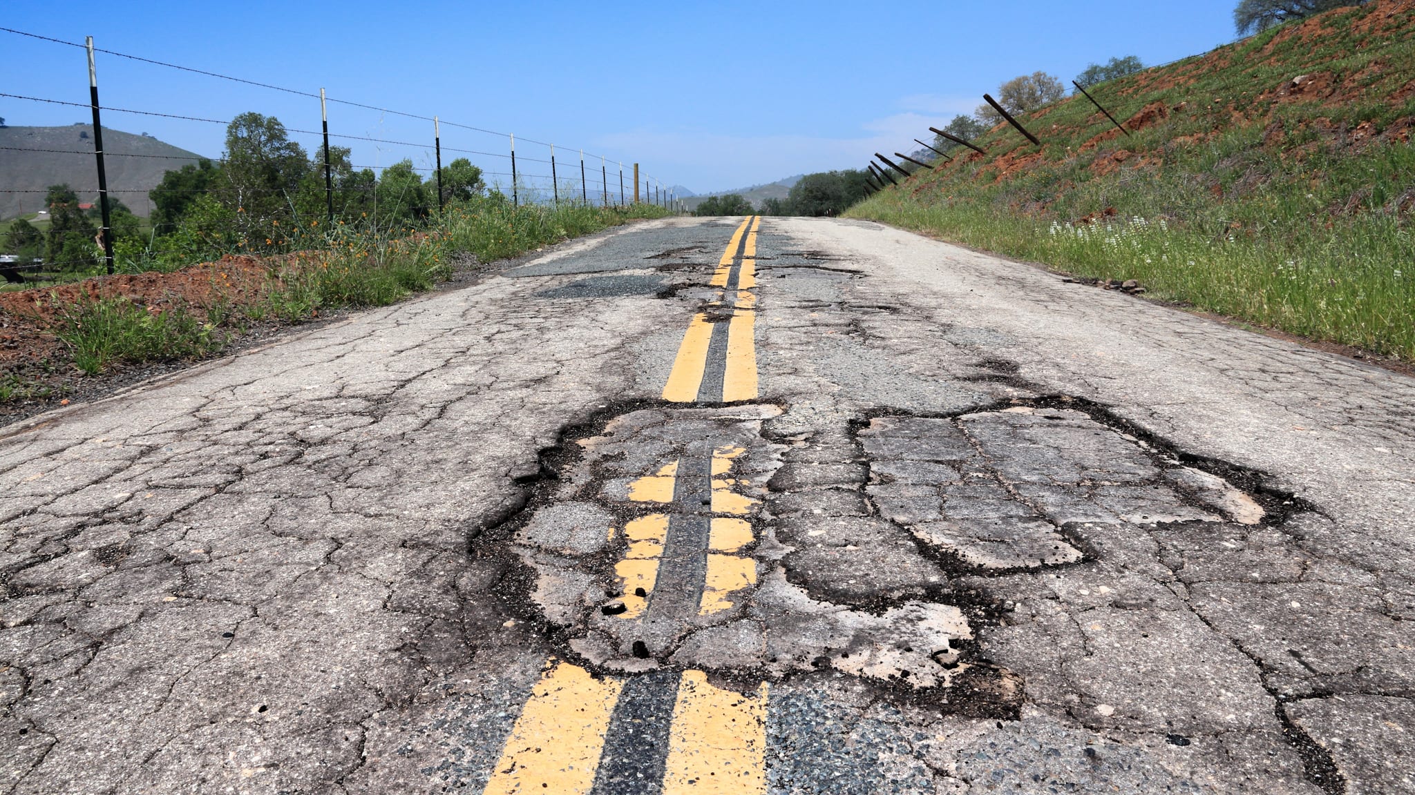 How a Pay-Per-Mile Tax Could Change Electric Car Ownership as Gas Tax Revenue Evaporates 3 Pothole road - damaged rural road surface in California, USA.
