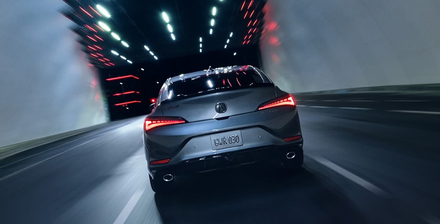 Rear view of a silver2025 Acura Integra driving at night