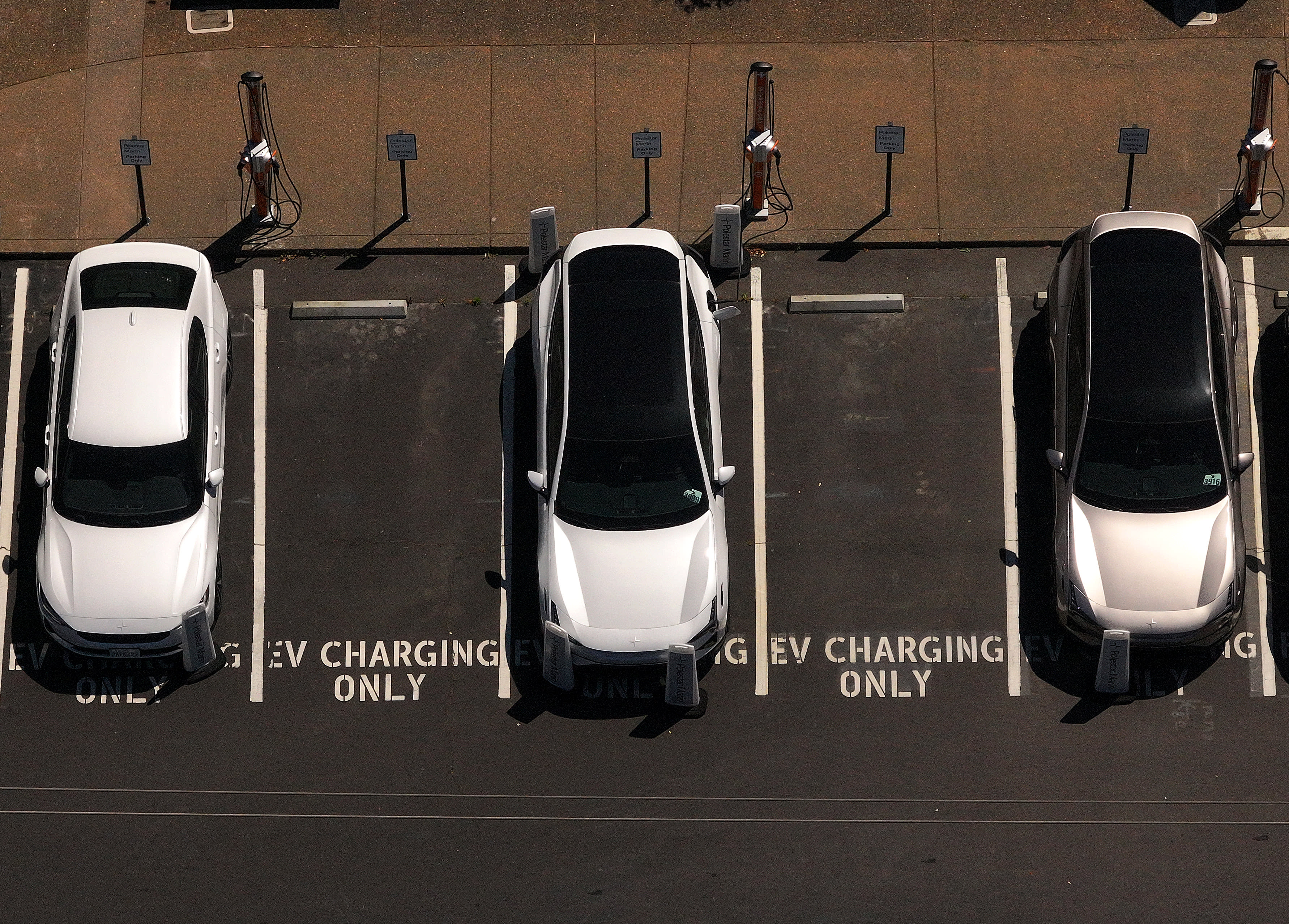 In an aerial view, electric cars sit parked at a charging station on May 19, 2025 in Corte Madera, California.